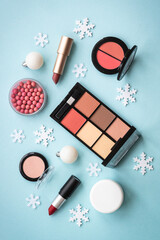 Make up products and christmas decorations on blue background. Top view image with copy space.