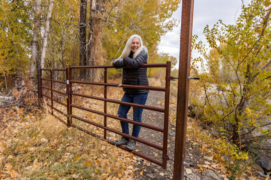 Senior blonde woman leaning on ranch gate&nbsp;