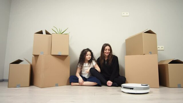 happy family mother and baby daughter in an empty apartment near the wall with cardboard boxes relocation