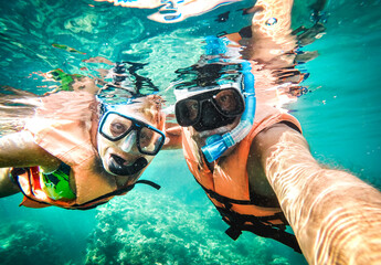 Active senior couple taking under water selfie in tropical sea excursion with water camera - Boat...