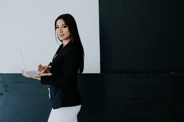 a business woman in a black jacket holds a laptop in her hands