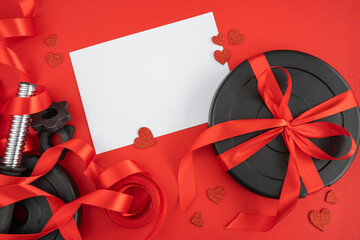 Ribbon wrapped gym dumbbell barbell weight plates, decorative red hearts and copy space on white...