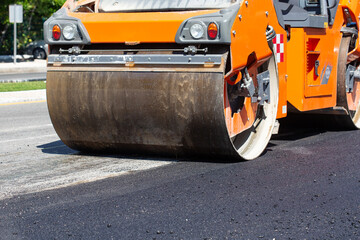 Road construction works with steamroller machine and asphalt finisher