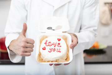 Close-up portrait of confectioner holding bento cake and showing thumbs up
