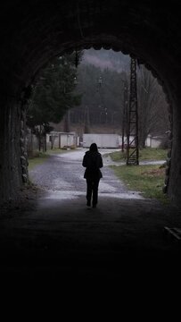 Unrecognizable woman walking out of a dark tunnel