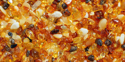Amber texture background, small stones yellow orange gradient color. Natural gemstone mineral for jewelry. Top view Amber textured fon. Sunstones pieces ancient resin. Transparent pieces gem.