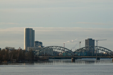 panorama of the city of riga, in the photo the railway bridge and high-rise buildings against the gray sky