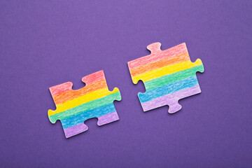 Concept LGBT as a part of society - two puzzle with the coloring of the flag of sexual minorities on violet background