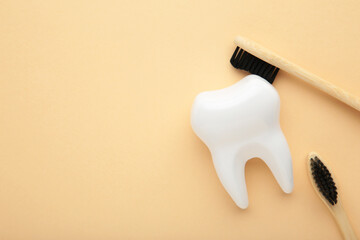 White healthy tooth model and toothbrushes on beige background. Dental care and healthcare concept.