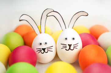 Funny bunnies couple on background of colorful eggs. Cheerful Easter background. Holiday card. Hunt 