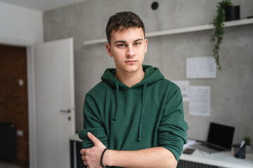 one man teenager stand in room at home wear green hoodie waist up