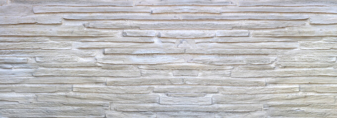 Struktur einer hellen Wandverkleidung aus langen groben Verblendsteinen mit großen Fugen