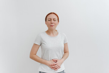 A young woman holds on to her stomach in pain. Digestive problems, gastrointestinal diseases concept. White backgroung.