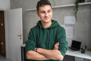 one man teenager stand in room at home wear green hoodie waist up