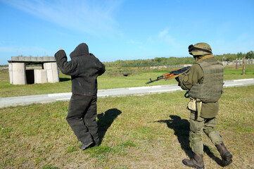 Armed soldier escorting arrested man, training. Ukraine