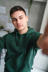 one man teenager stand in room at home wear green hoodie UGC selfie