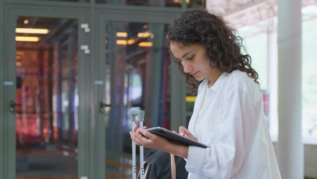 waiting train on railway station, portrait of young woman with tablet, checking messages in app