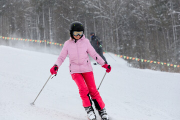 Girl skiing on snowing track in ski resort