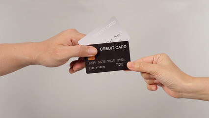 The hand holds two credit card and another hand is choosing on white background.