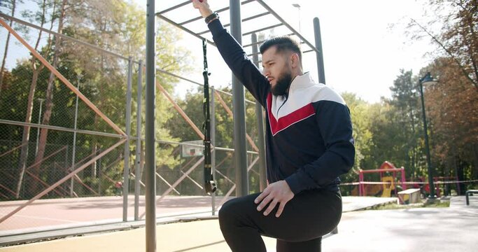 Gym health outside concept. Trainer male correcting fit does gym exercises with rubber band . Outdoor Athletic man does exercises with elastic band. Attractive fitness man does exercising outside.