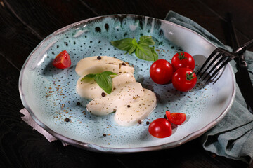Traditional italian plate with white mozzarella, cherry tomato, basil and olive oil.