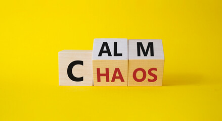 Calm vs chaos symbol. Turned wooden cubes with words Chaos and Calm. Beautiful yellow background. Business and Calm vs chaos concept. Copy space.