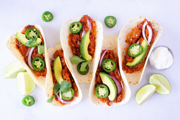 Jack fruit vegan tacos. Above view over a white marble background. Healthy eating, plant-based pulled pork meat substitute. - obrazy, fototapety, plakaty