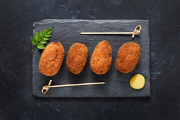 Overhead voew of gourmet style ham croquette with black background.