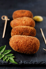 Portrait of gourmet style ham croquettes with black background.