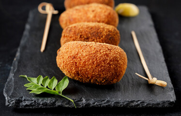 Close-up of gourmet-style ham croquettes with a black background.
