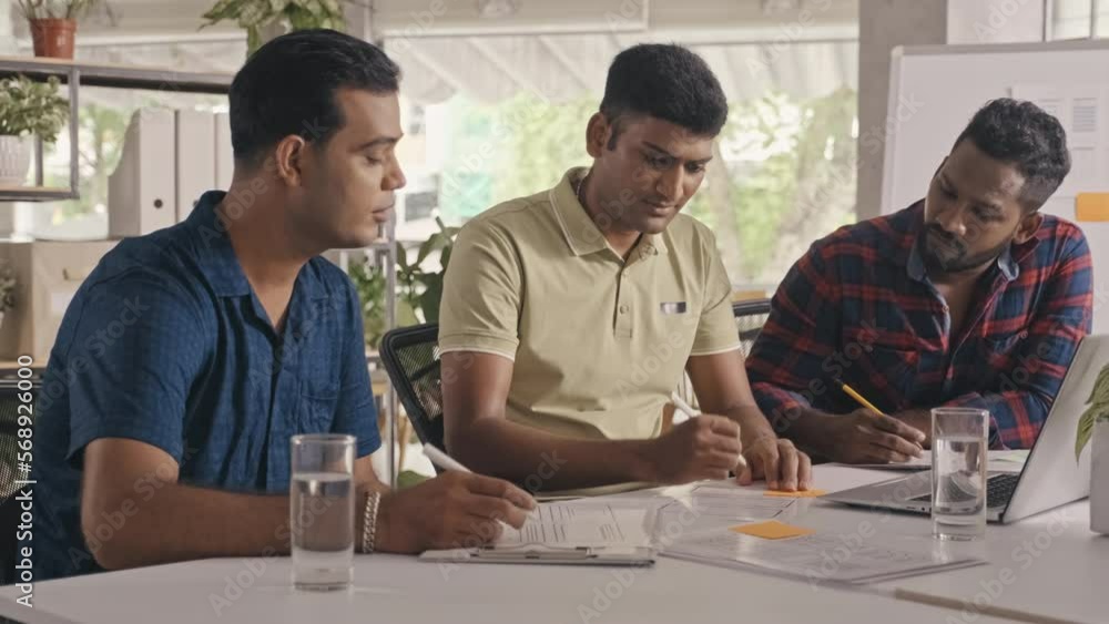 Wall mural medium shot of team of indian software developers discussing it project and taking notes during offi