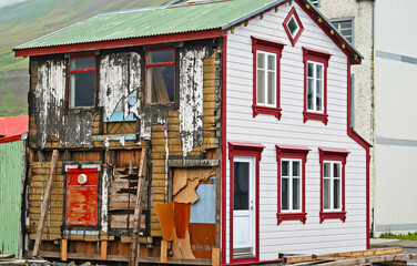 Siglufjördur, Iceland - 9. July 2008: Half partly renovated typical wood house with new front facade, old weathered sidewall - obrazy, fototapety, plakaty