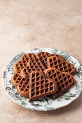 Heart form chocolate waffle cookies in festive plate for Valentine's day on beige background with copy space. Sweet gift with love