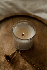 Burning candle on a wooden tray on the bed. Cozy house. Decor, details.