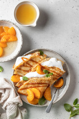 Crepes with fresh mandarin, caramel, cream in the filling and mint leaves on white textured background. Maslenitsa or Pancake week traditional concept. Top view, text space, flat lay