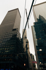 low angle view of electric wires and contemporary buildings with glass facades in New York City.
