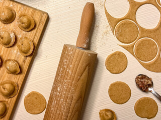 Cooking dumplings from whole grain flour. Dough, dumplings on a wooden board, a wooden rolling pin,...
