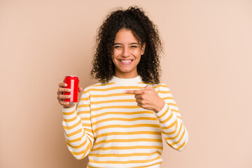 Young african american woman holding a cola refreshment isolated person pointing by hand to a shirt...