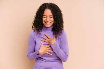 Fototapeta premium Young african american curly woman isolated laughs happily and has fun keeping hands on stomach.