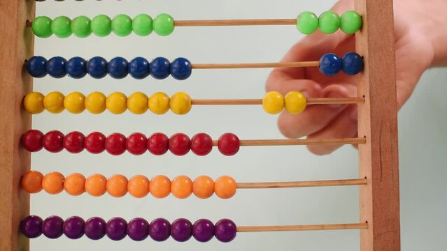 Hand working with a colorful wooden abacus on green background