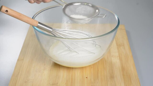 Pour the flour through a sieve into the beaten eggs. Making dough for dessert. High quality 4k footage
