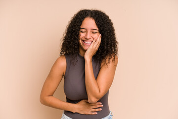 Young african american curly woman isolated laughs happily and has fun keeping hands on stomach.