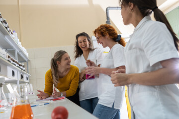 Group of female chemistry scientists and students on coffee break. They're standing at the lap and...