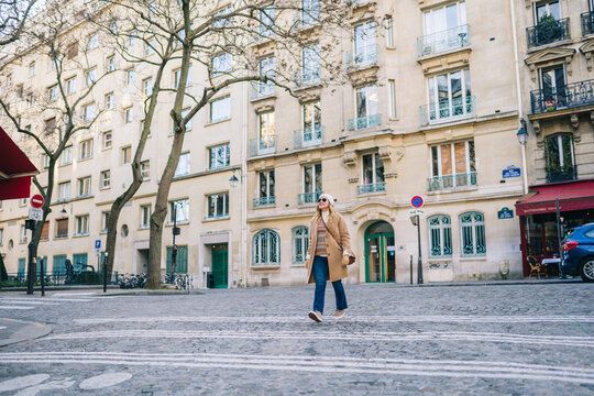 Positive young woman smiling an walking on paved street