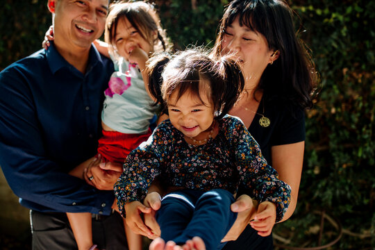 Laughing Young Asian Family Outdoors Together