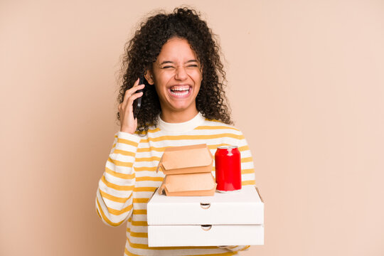 Young African American Woman Holding A Pizza And Burger Fast Food Calling With Mobile Phone Isolated