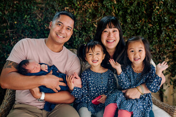 happy family with newborn baby and toddlers sitting close together