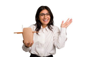 Young business indian woman eating takeaway noodles cut out isolated receiving a pleasant surprise, excited and raising hands.