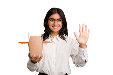 Young business indian woman eating takeaway noodles cut out isolated smiling cheerful showing number five with fingers.