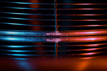Close up shot of fried oil strainer on black background illuminated in colorful lights, abstract...